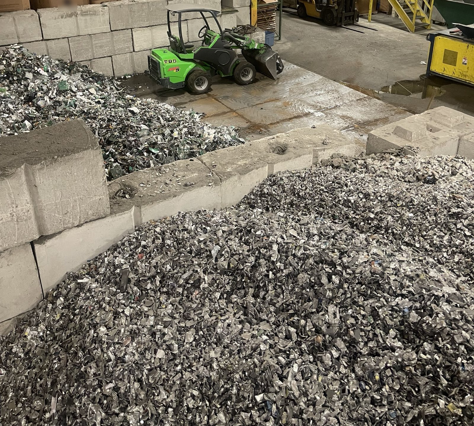 Piles of shredded metal and shredded circuit boards in concrete bays on the plant floor