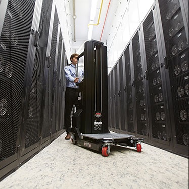 Technician moving a server rack through a data centre aisle